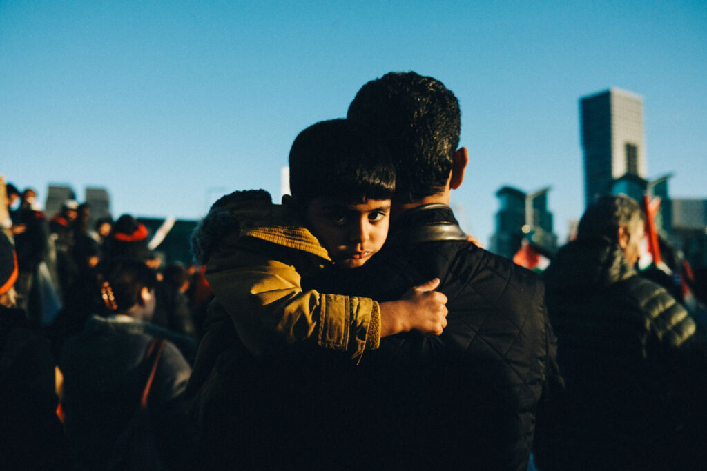 Immigrant man holding a young child. Photo by Joseph Lockley on Unsplash