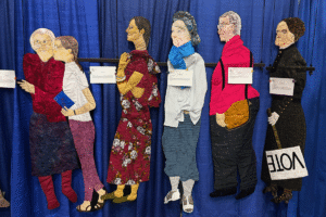 Quilted images of people standing in line to vote